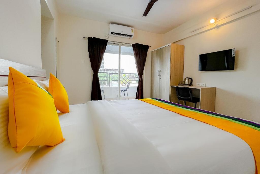 a bedroom with a large white bed with yellow pillows at Itsy By Treebo - Opal Suites in Pune