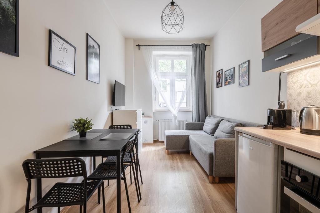 a kitchen and living room with a table and a couch at RentPlanet - Studio Nadodrze in Wrocław