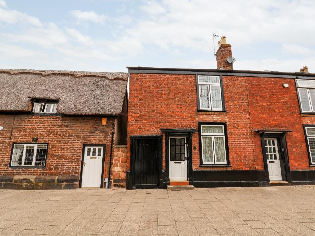 a brick building with white doors and a clock tower at 91 Main Street in Frodsham