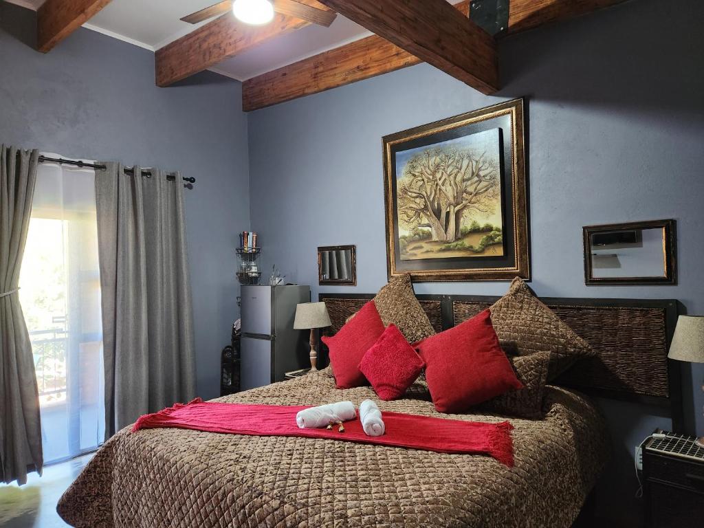 a bedroom with a large bed with red pillows at Suikerbosrant Sleep and go in Pretoria