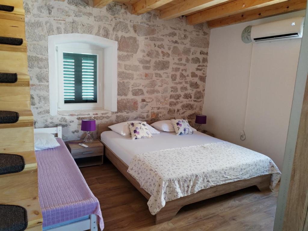 a bedroom with a bed and a brick wall at Ema in Prvić Šepurine
