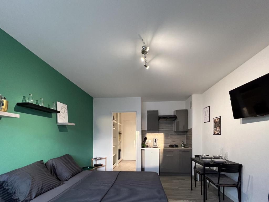 - une chambre avec un lit et un mur vert dans l'établissement Studio Le Maréchal - Près frontière et Netflix, à Huningue