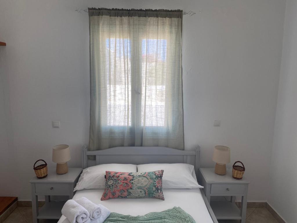 a bedroom with a bed and a window with towels at MARGARITA STUDIOS in Antiparos