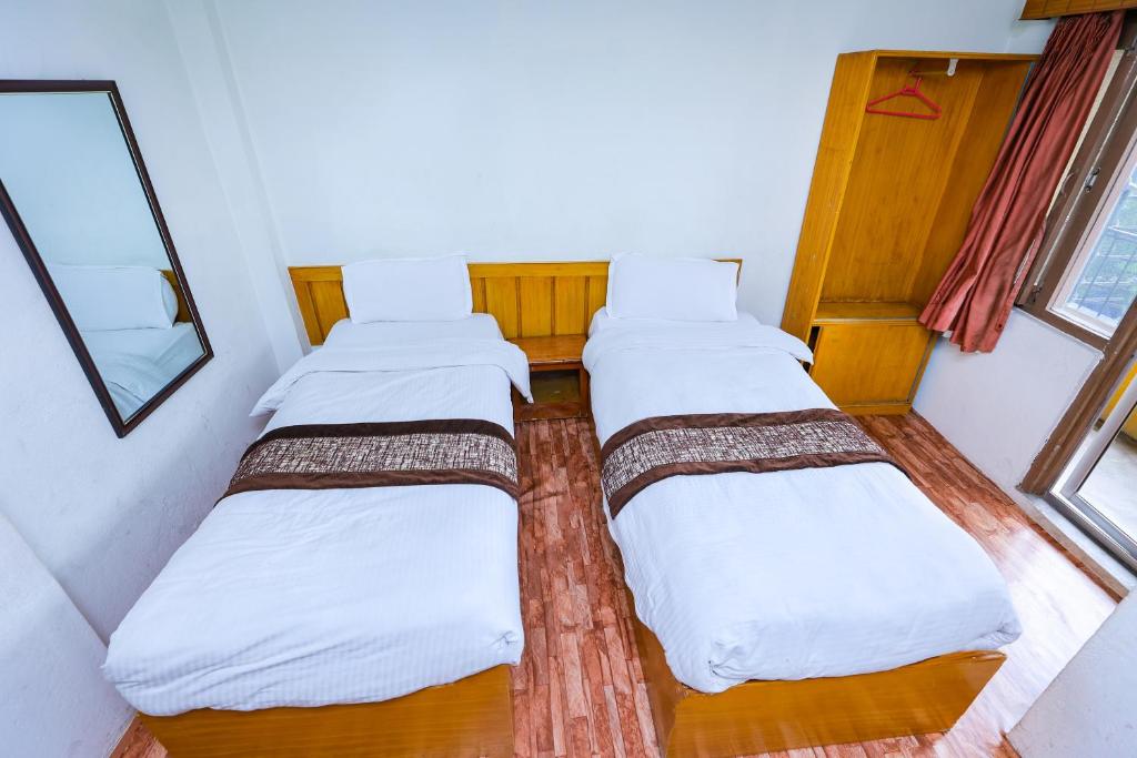 2 camas en una habitación pequeña con ventana en Hotel Nana, en Katmandú