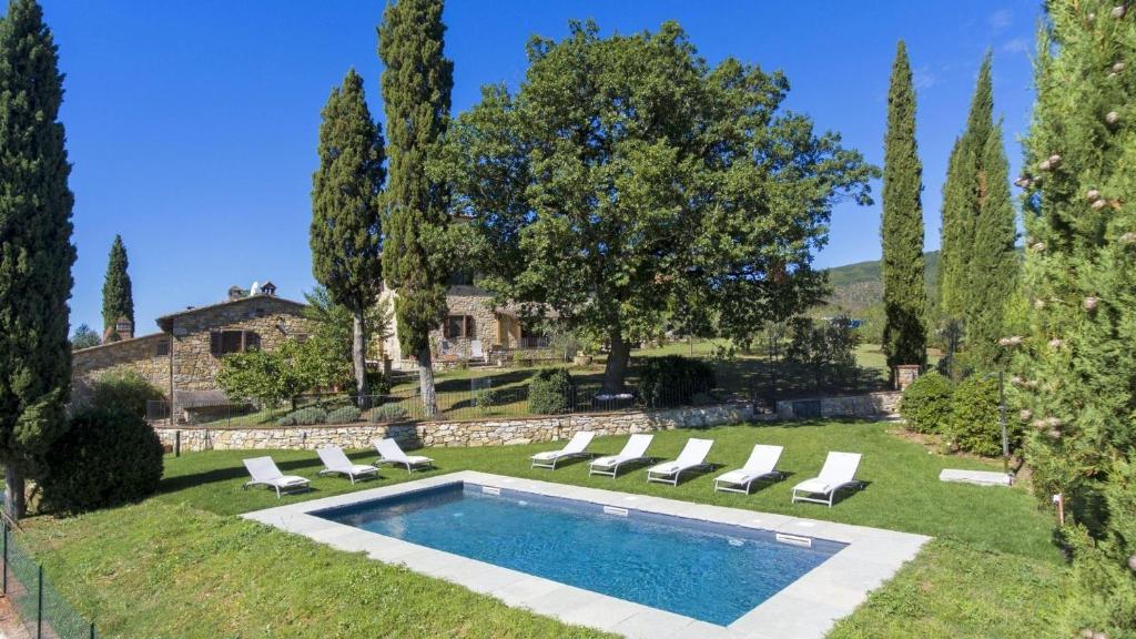 a pool in a yard with lounge chairs and a house at Fico del Corno in Radda in Chianti