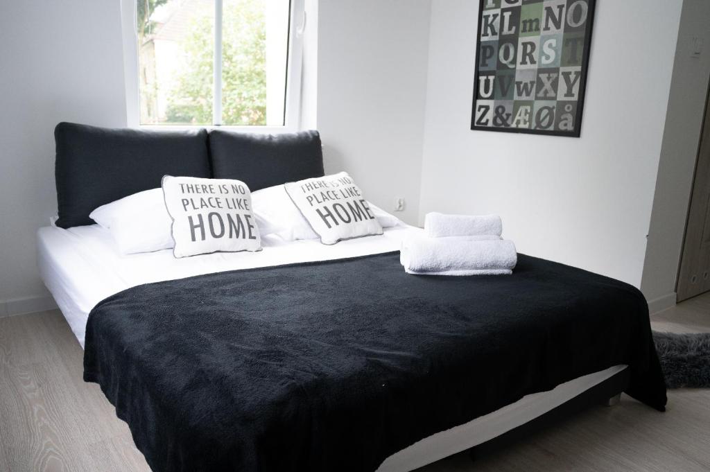 Una cama blanca y negra con almohadas. en Niron Apartament Niepodległości, en Piła