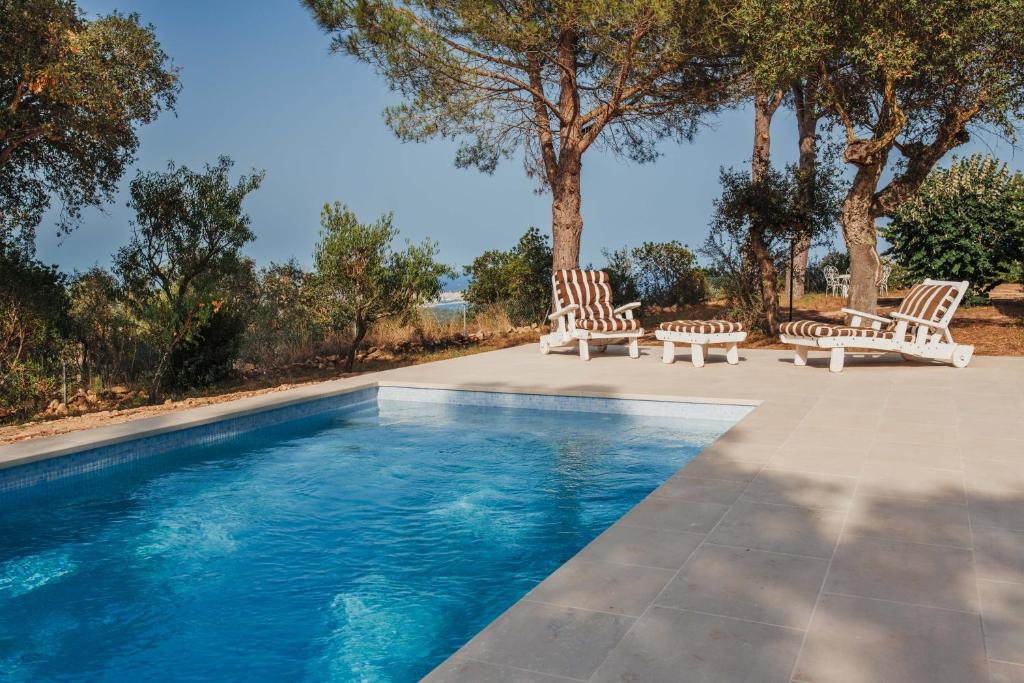 a swimming pool with two chairs and a table at Villa Ventisca in Platja  d'Aro
