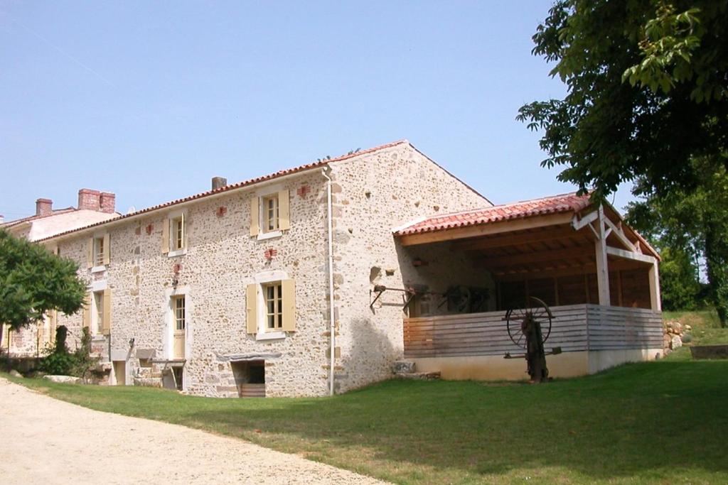 a large stone building with a porch on the side of it at le Moulin de Garreau in Saint-Martin-des-Fontaines