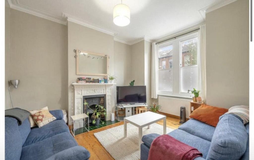 a living room with two blue couches and a fireplace at Luxury Flat in the heart of South London in London