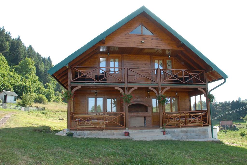 a large wooden house with a large balcony on a field at Planinska kuća Jovanić in Nova Varoš