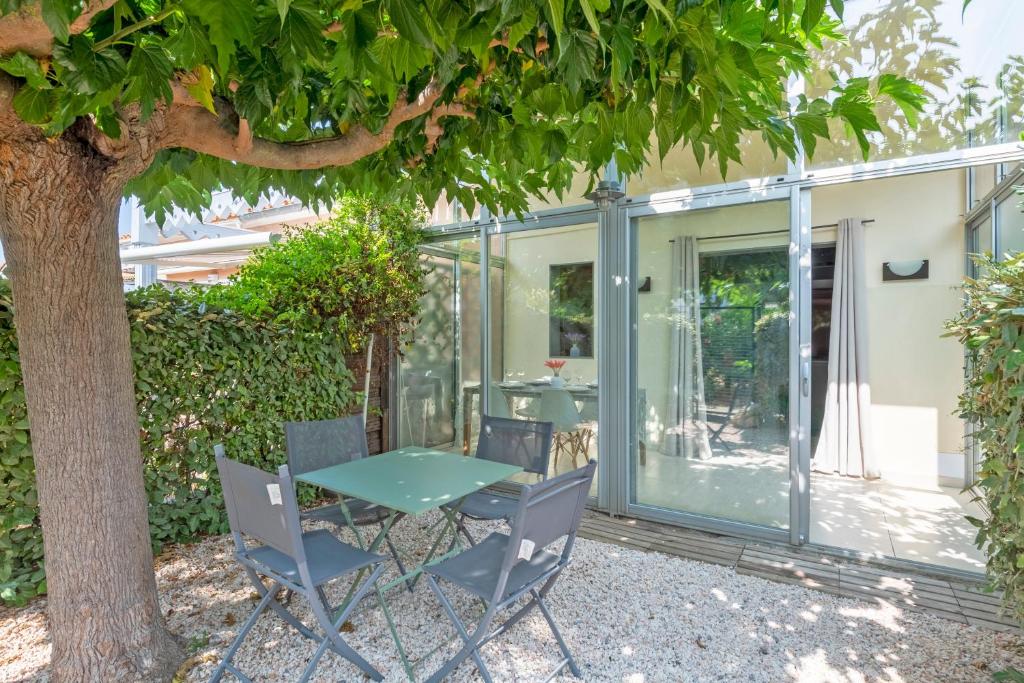 une maison en verre avec une table et des chaises sous un arbre dans l'établissement Le Scarlett - Maison à 300m de la plage, à Palavas-les-Flots