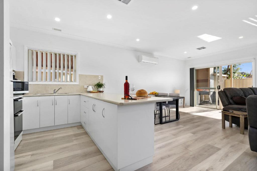 a kitchen and living room with white cabinets and a counter at The Shamrock House A in Renmark