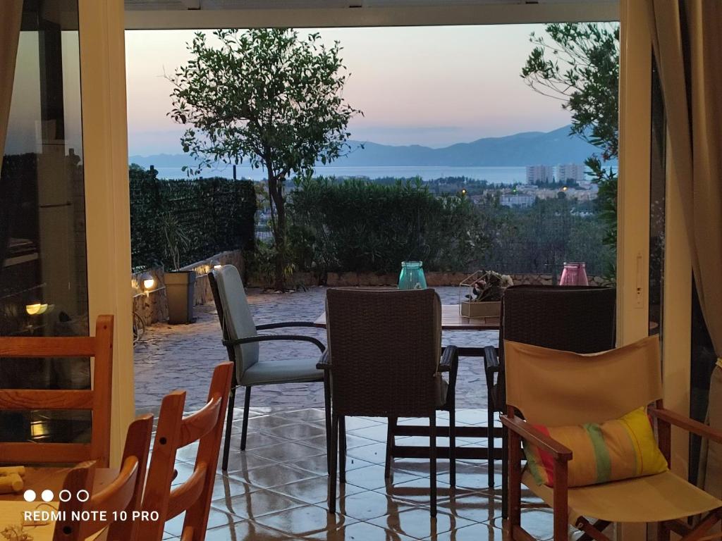 eine Terrasse mit Stühlen und einem Tisch mit Aussicht in der Unterkunft Andrew's sunset view apartment in Loutraki