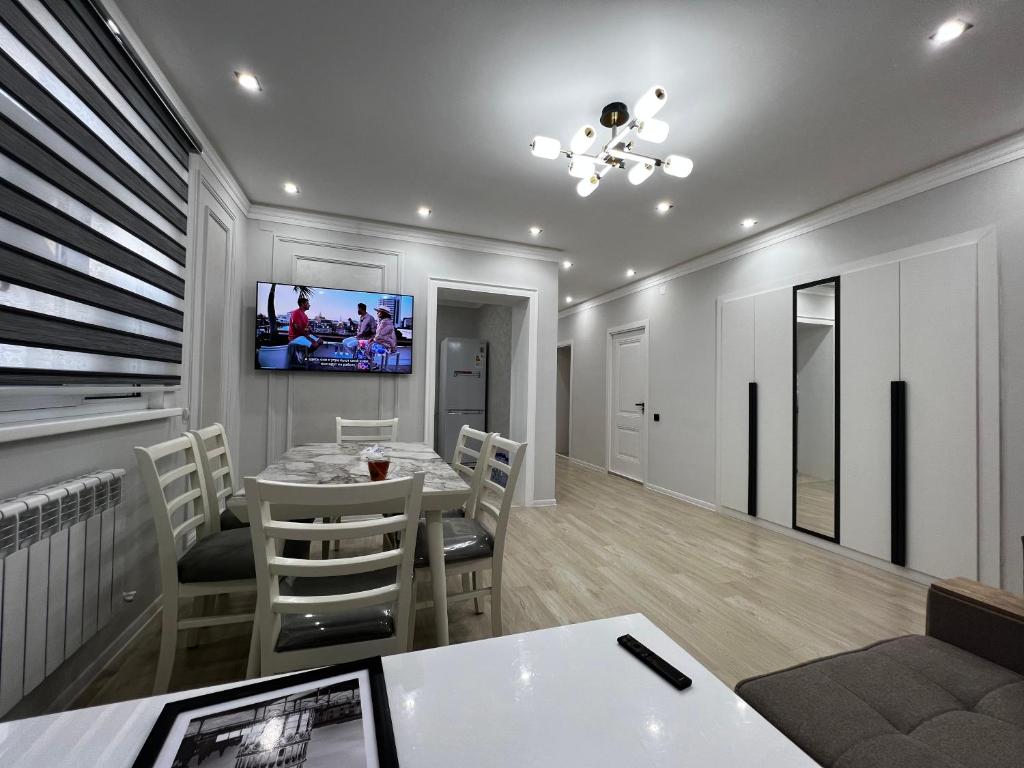 a dining room with a table and a tv on the wall at Entire Apartment in Central Nukus in Nukus