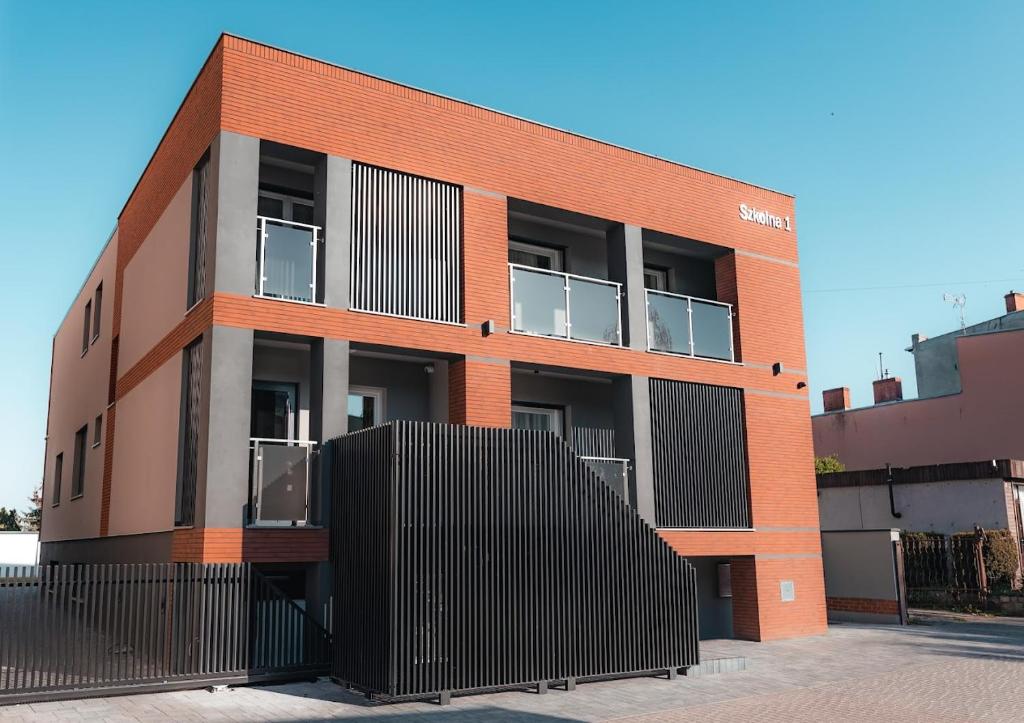 a brick building with a black fence in front of it at Apartamenty Szkolna in Żnin