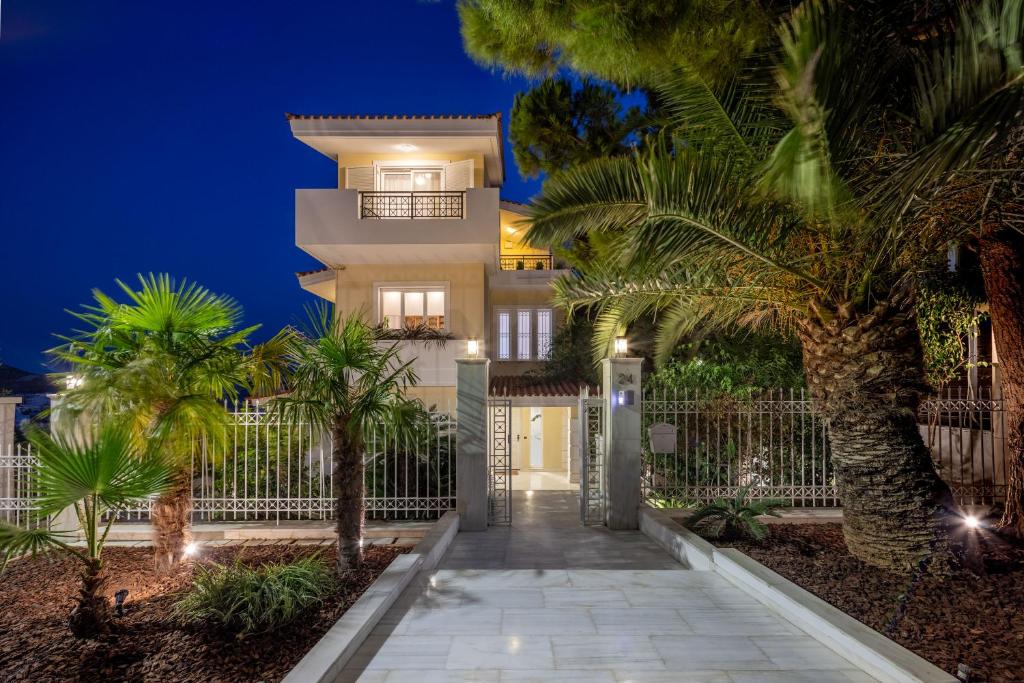 a villa with a gate and palm trees at night at The Southern Mansion Athens in Athens