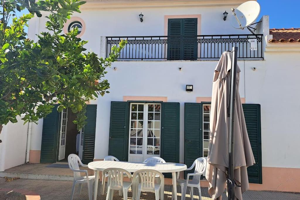 un tavolo con sedie e un ombrellone di fronte a un edificio di Casa Melides a Melides