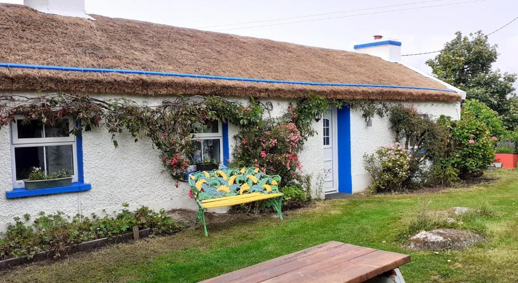 a house with a yellow bench in front of it at The Rockhouse - Cosy stone built Thatch Cottage in Dungloe
