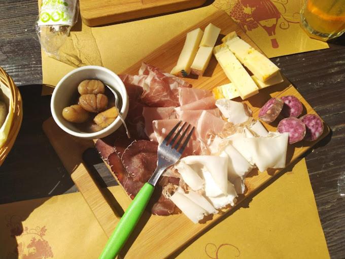 a cutting board with meat and cheese and a knife and fork at Home Cervino Apartments in Antey-Saint-André