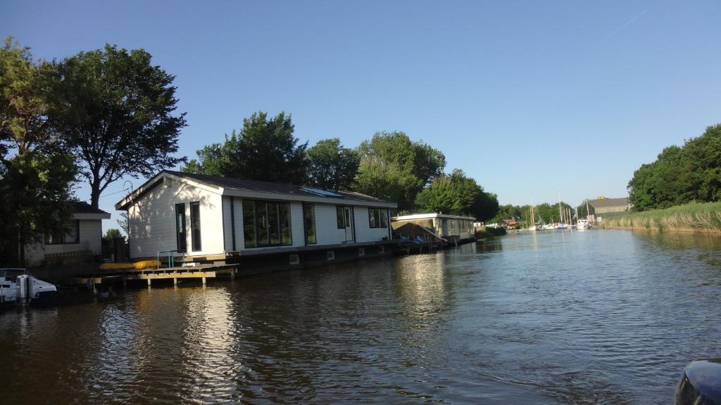 a house on a dock in the middle of a river at BB de Woonboot in Anna Paulowna