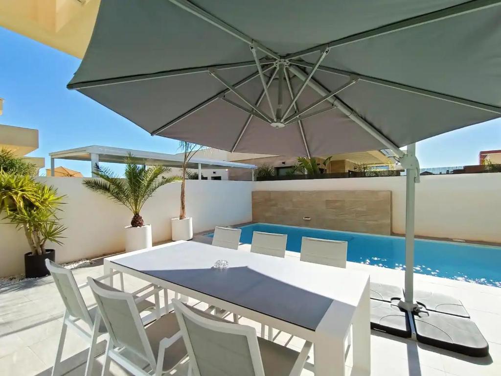 un patio con mesa, sillas y sombrilla en Neubauvilla mit Pool Los Montesinos, en Los Montesinos