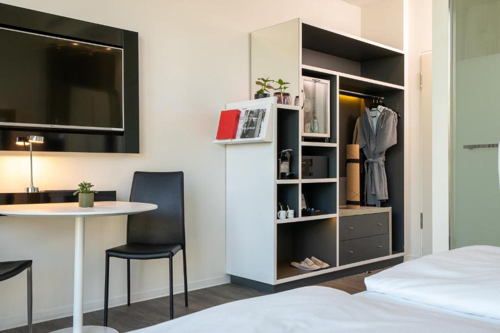a room with a bed and a desk and a table at INNSiDE by Meliá Leipzig in Leipzig