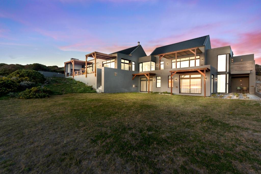 une grande maison avec une grande cour en face dans l'établissement Romansbaai Moksha on the Sea, à Gansbaai