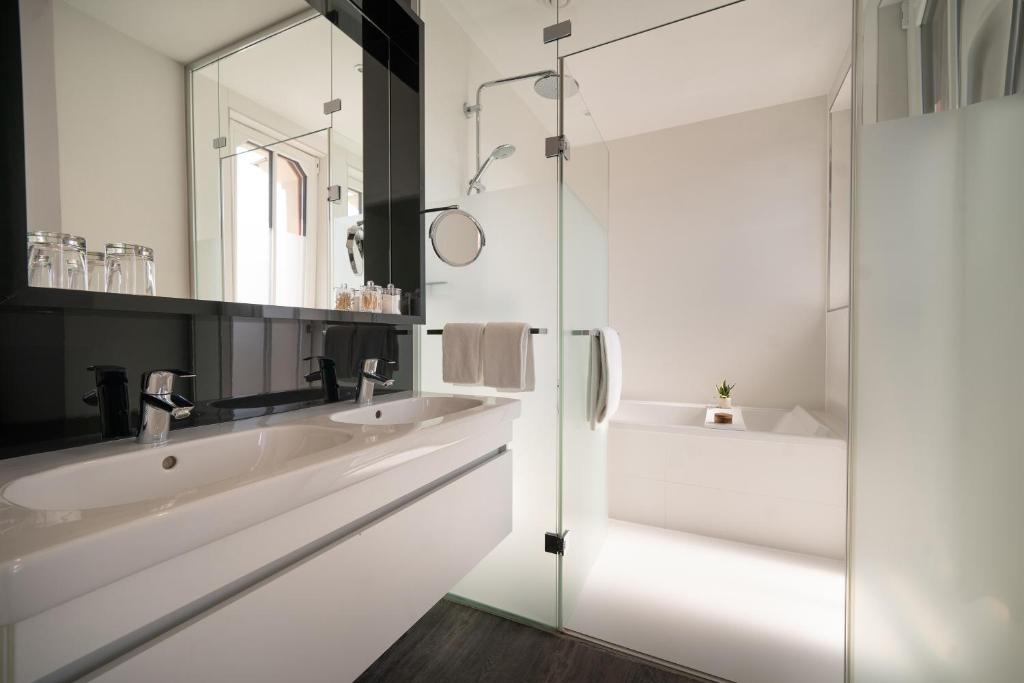 a white bathroom with two sinks and a mirror at INNSiDE by Meliá Leipzig in Leipzig
