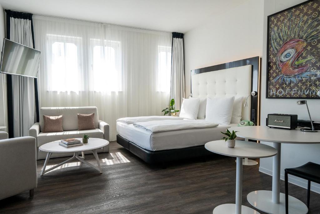 a bedroom with a bed and a couch and tables at INNSiDE by Meliá Leipzig in Leipzig