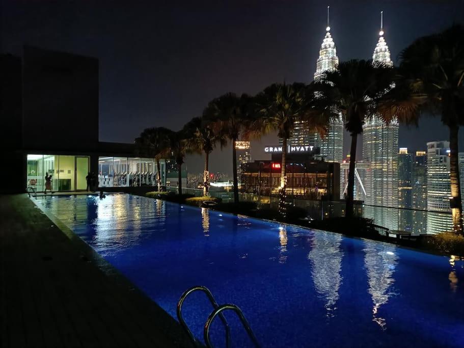 uma grande piscina com um horizonte da cidade à noite em Lovely 3 Rooms with KLCC View, Pavilion & Netflix em Kuala Lumpur