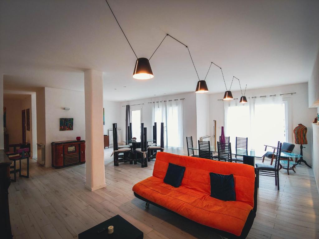 a living room with an orange couch and a dining room at Casa di Marina, tra Etna e mare. in Gravina di Catania