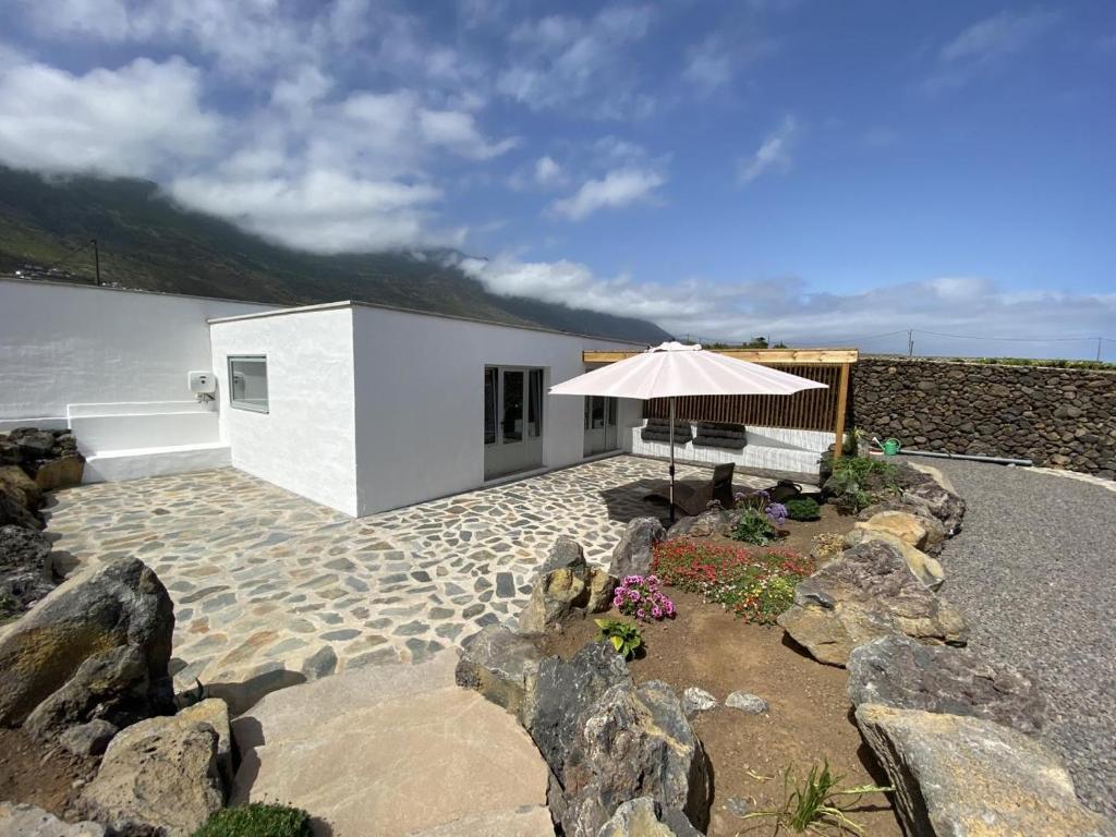 een wit gebouw met een paraplu en enkele rotsen bij Casa de La Maceta in Frontera