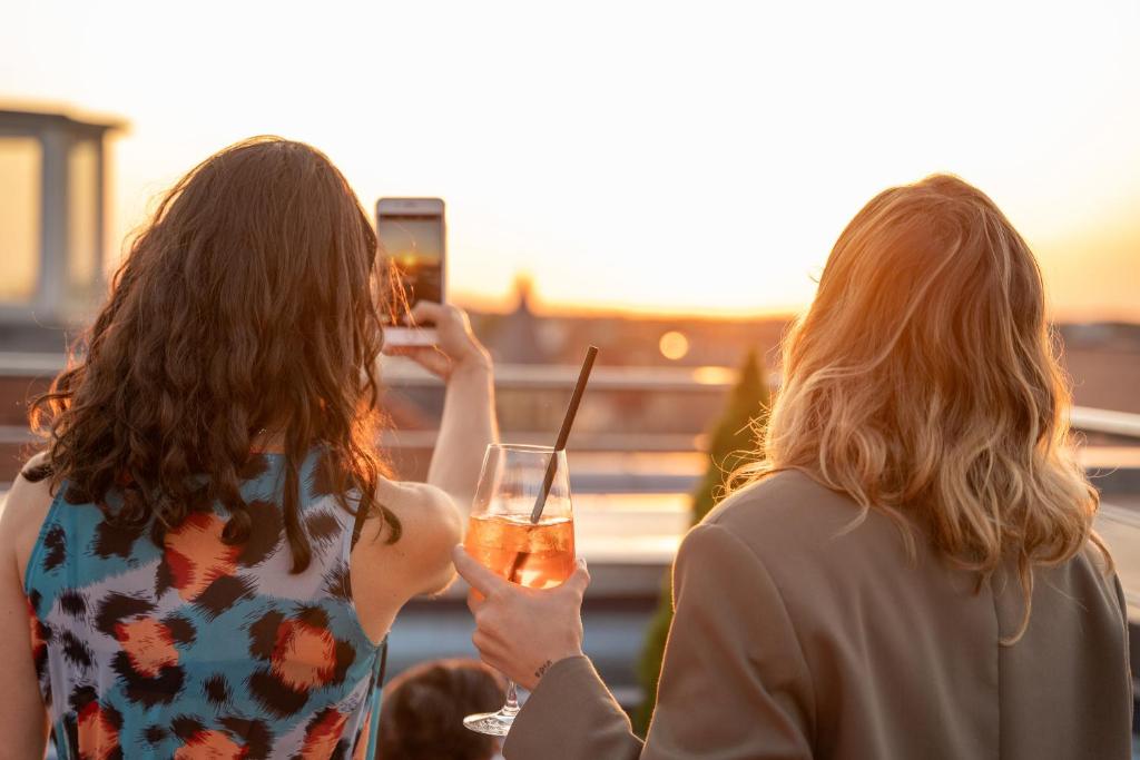 two women standing next to each other holding a drink at INNSiDE by Meliá Leipzig in Leipzig