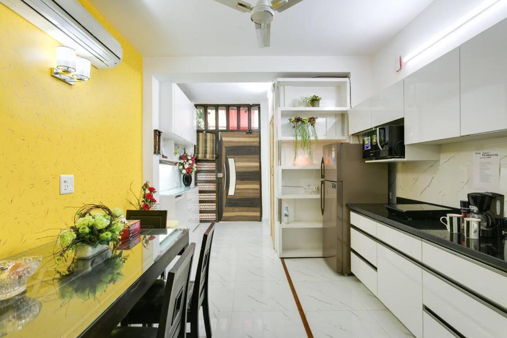 a kitchen with white cabinets and a yellow wall at Moydom Nice & Cosy Private 1 BHK Apartment OPP NFC market in New Delhi