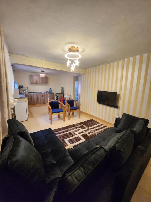 uma sala de estar com um sofá preto e uma cozinha em Zuri homes 1 em Kagio