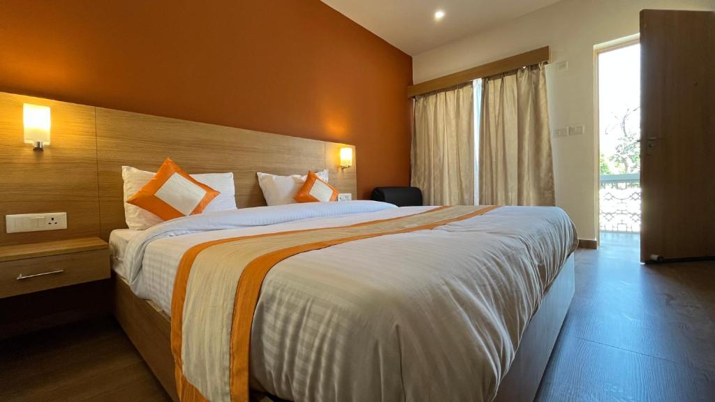 Habitación de hotel con cama grande y paredes de color naranja en Hotel The Bundela - Khajuraho, Madhya Pradesh, en Khajurāho