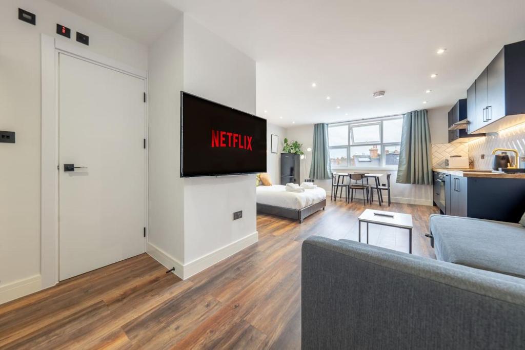 倫敦的住宿－3 West London Brand New Loft，客厅配有沙发和墙上的电视