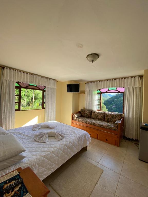 ein Schlafzimmer mit einem Bett und zwei Fenstern in der Unterkunft Casa Mara in Nova Friburgo