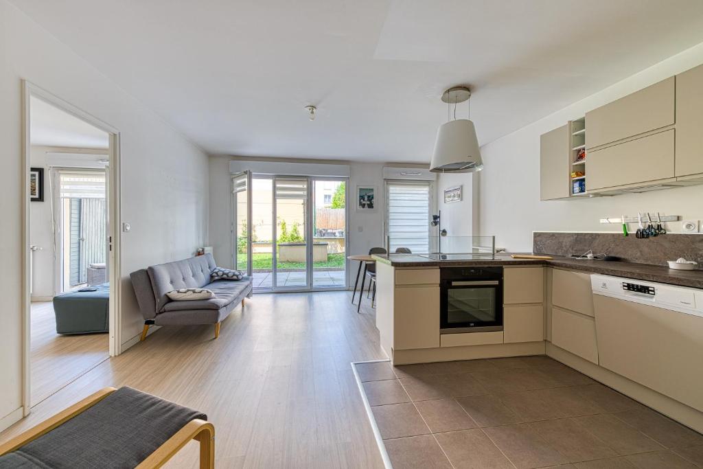 Il dispose d'une cuisine ouverte et d'un salon avec un canapé. dans l'établissement Le St Gratien - Appartement avec jardin, à Épinay-sur-Seine