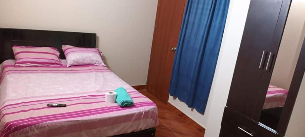 Schlafzimmer mit einem Bett mit lila und rosa Bettwäsche in der Unterkunft HOSPEDAJE NELLY in Malabrigo