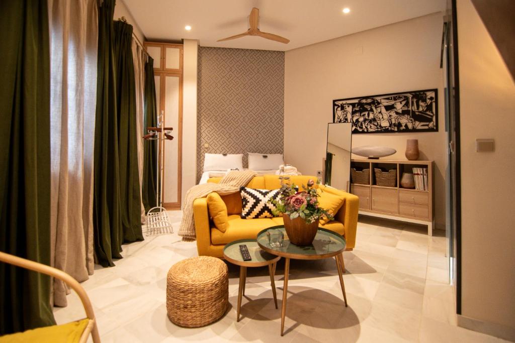ein Wohnzimmer mit einem gelben Sofa und einem Bett in der Unterkunft The Terrace, dúplex con terraza privada in Sevilla
