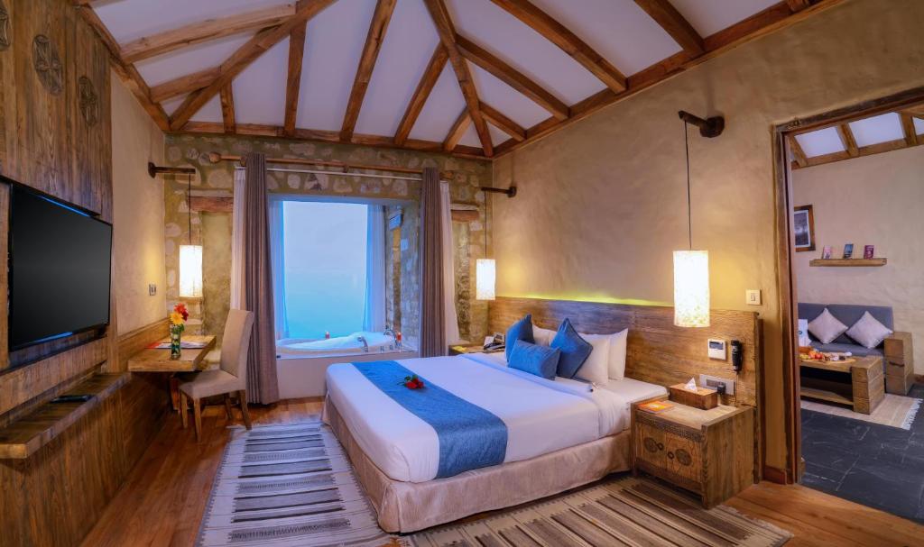 a bedroom with a large bed and a television at Sarangkot Mountain Lodge in Pokhara