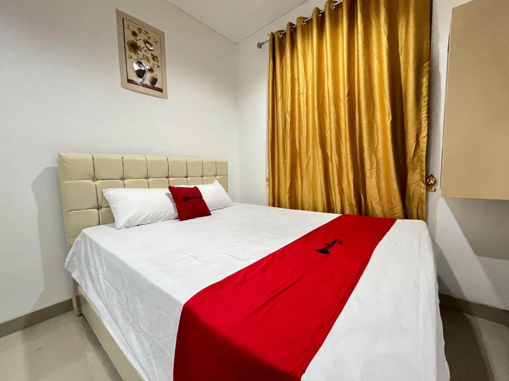Un dormitorio con una cama roja y blanca y una ventana en RedDoorz at Ring Road II Area Manado en Paniki