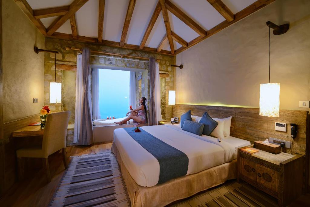 a bedroom with a bed and a woman sitting in the tub at Sarangkot Mountain Lodge in Pokhara