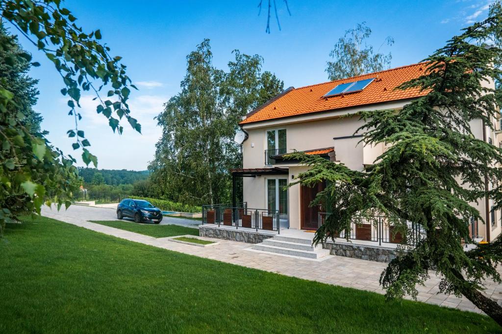 ein Haus mit einem orangenen Dach und einem Auto auf einer Straße in der Unterkunft Vikendica Aleksandrović Meterize in Topola