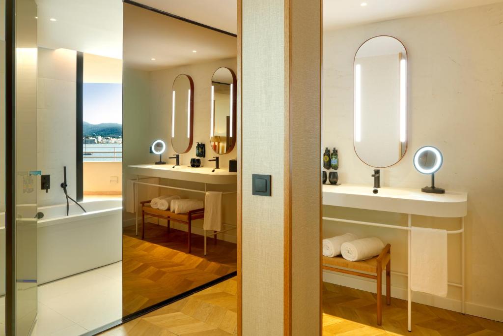 a bathroom with two sinks and two mirrors at TRS Ibiza Hotel - Adults Only in San Antonio
