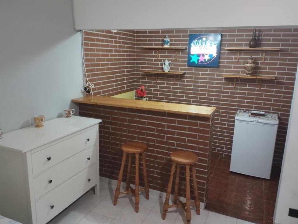 una cucina con due sgabelli e un muro di mattoni di Quarto Privado Grande Completo a Agualva