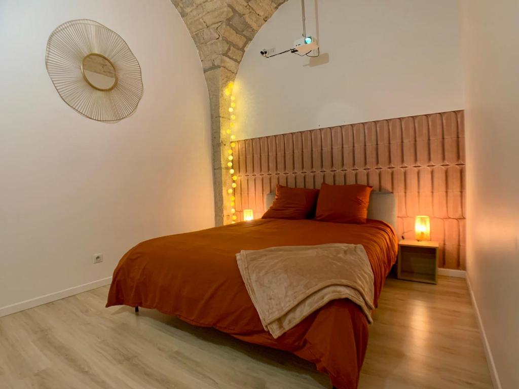 ディジョンにあるLOFT Spa Gare Cité Gastronomique Dijonの石壁のベッドルーム1室(大きなオレンジ色のベッド1台付)