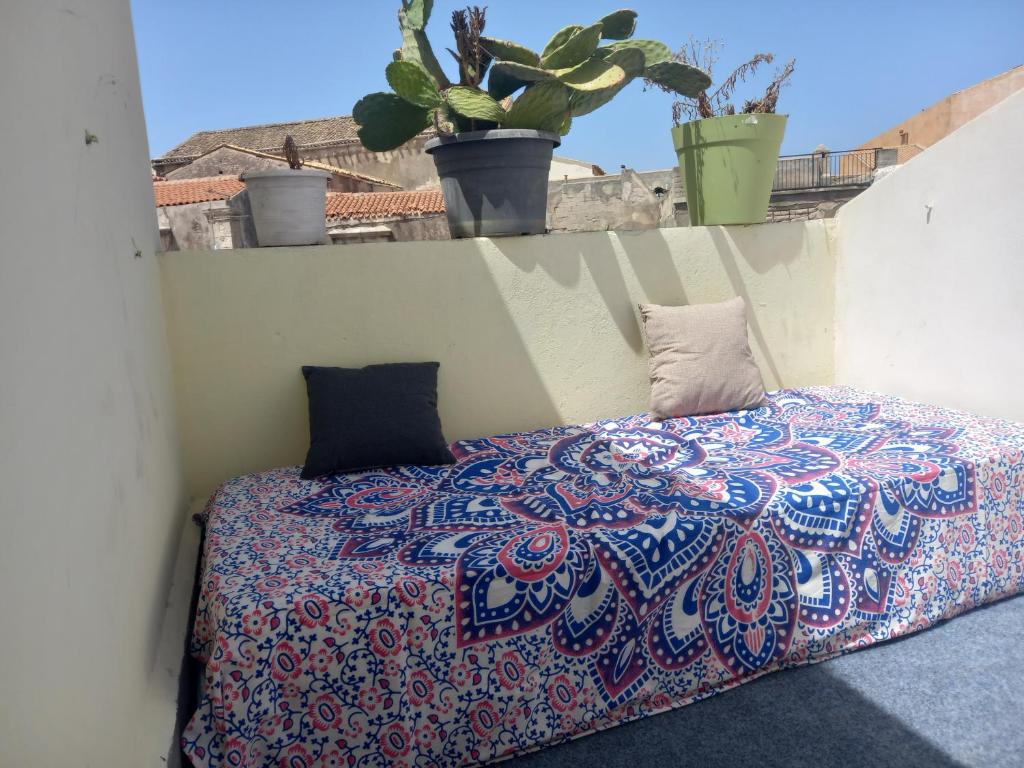 uma cama num quarto com plantas numa varanda em Casa dei fiori em Siracusa
