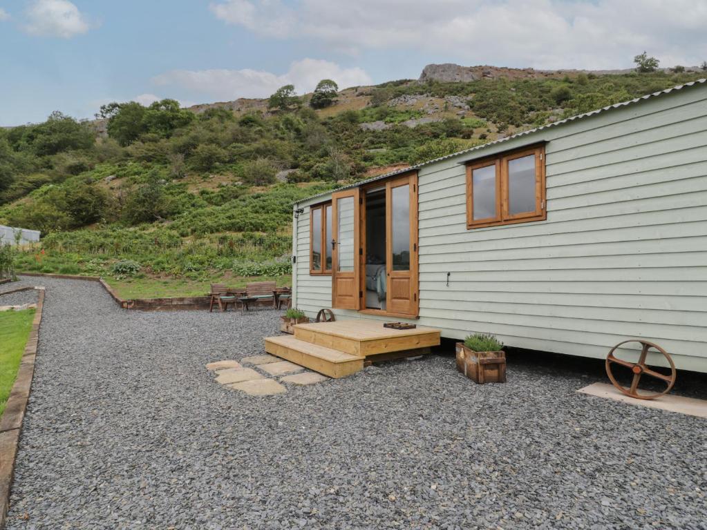 a tiny house with a bench and a patio at Tan Y Castell Shepherds Hut in Llangollen